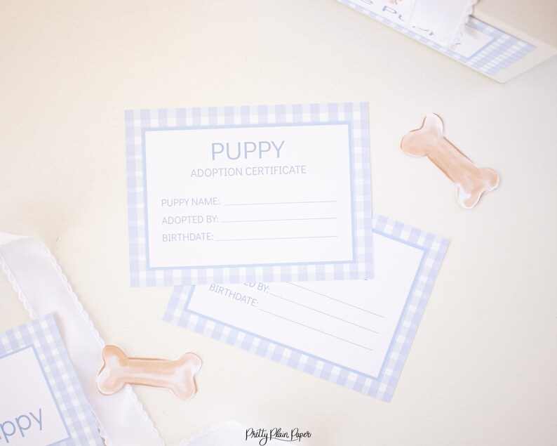 May include: A blue and white gingham puppy adoption certificate with the text "PUPPY ADOPTION CERTIFICATE" and spaces for the puppy's name, adopted by, and birthdate.