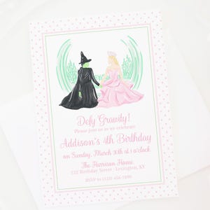 Pode incluir: Um convite rosa e verde com fundo branco e bolinhas rosa. O convite apresenta uma ilustração em aquarela da Bruxa Má do Oeste e Glinda a Boa Bruxa do Mágico de Oz. O texto diz "Defy Gravity! Please join us as we celebrate Addison's 4th Birthday on Sunday, March 30th at 1 o'clock. The Harrison Home 123 Birthday Street Lexington, KY RSVP to (123) 456-7890".