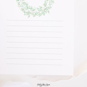 May include: A white sheet of paper with a green floral wreath at the top and lined with horizontal lines. The text "Pretty Plain Paper" is at the bottom of the page.