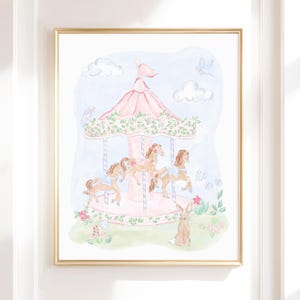 May include: Watercolour painting of a carousel with pink and tan horses, a pink canopy, and a light blue sky with clouds. A brown rabbit sits in the grass. The artwork is framed in a gold-coloured frame.