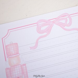 May include: Pink and white gingham patterned nutcracker with a pink bow on a pink and white lined paper. The text "Pretty Plain Paper" is at the bottom of the page.