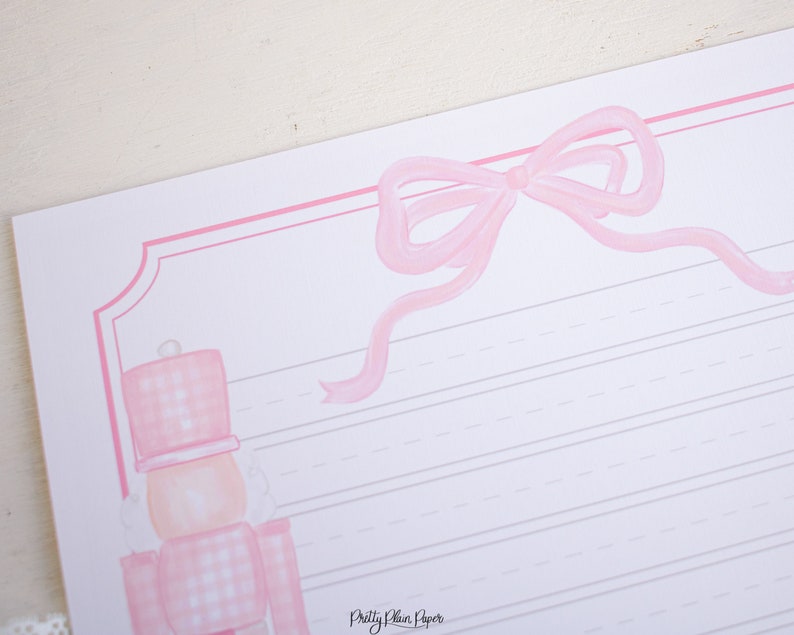 May include: Pink and white gingham patterned nutcracker with a pink bow on a pink and white lined paper. The text "Pretty Plain Paper" is at the bottom of the page.
