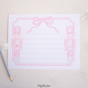 May include: Printable pink and white lined paper with a pink bow and two pink nutcracker illustrations. The paper has the text "Pretty Plain Paper" at the bottom.