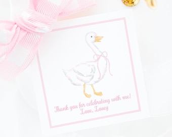 Könnte beinhalten: Eine weiße quadratische Karte mit rosa Rand zeigt eine Aquarellillustration einer Gans mit einer rosa Schleife. Die Karte enthält den Text "Thank you for celebrating with me! Love, Lovey." Eine rosa-weiß karierte Schleife ist sichtbar.
