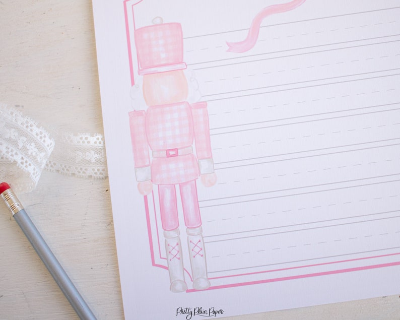 May include: A pink and white gingham nutcracker with a pink ribbon and a white background. The nutcracker is standing on a white surface. The text "Pretty Plain Paper" is at the bottom of the image.