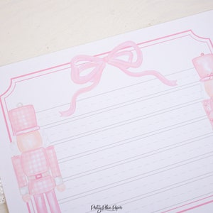 May include: Pink and white lined stationery paper with a pink bow and two pink nutcracker illustrations. The paper has the text "Pretty Plain Paper" at the bottom.