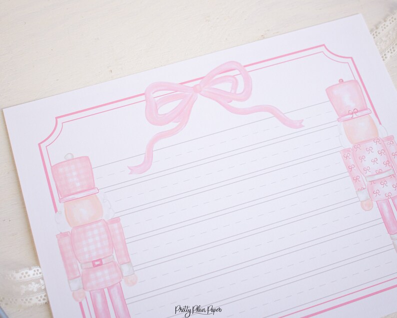 May include: Pink and white lined stationery paper with a pink bow and two pink nutcracker illustrations. The paper has the text "Pretty Plain Paper" at the bottom.