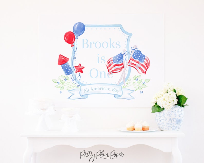 May include: A watercolor illustration of a blue and white shield with the text "Brooks is One All American Boy". The shield is decorated with red, white, and blue stars, balloons, and flags.