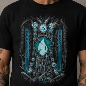 May include: Black t-shirt with a teal and grey graphic design. The artwork features a central teardrop shape, surrounded by detailed organic patterns, stylized eyes, and vertical blue elements with text. The design has a fantasy theme.