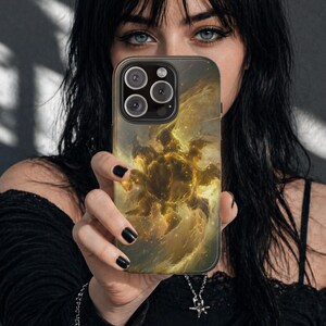 May include: A smartphone case featuring a golden nebula design. The case has a dark background with a swirling pattern of gold and yellow hues. The phone case has a camera module with three lenses.