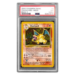 Puede incluir: Una taza de cerámica blanca con asa negra y el texto "But First, Coffee" en negrita negra. La taza se encuentra sobre un fondo borroso, sugiriendo un ambiente acogedor.