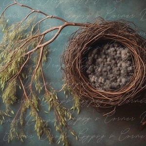 May include: A brown twig nest with a grey fluffy lining sits on a blue textured background. A branch with green leaves hangs over the nest.