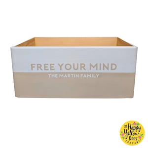 May include: A white wooden box with a beige top. The box has the text "FREE YOUR MIND" in beige lettering and "THE MARTIN FAMILY" in smaller beige lettering below.