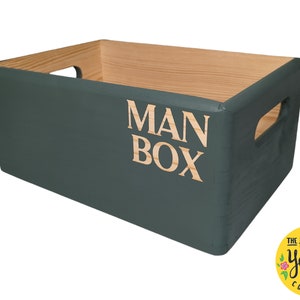 May include: A dark green wooden storage box with the words "MAN BOX" printed on the front in a light wood colour. The box has two handles on the sides.