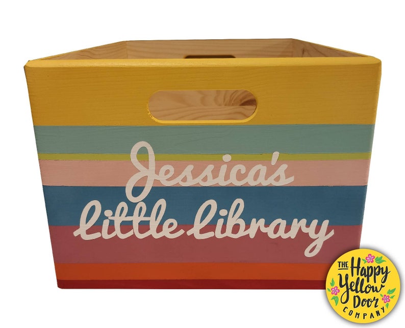 May include: A wooden storage crate featuring horizontal stripes in yellow, teal, light green, pink, blue, and orange. The front displays the white text "Jessica's little library" and includes a cutout handle at the top center of the box.