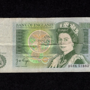 May include: A green Bank of England one pound banknote featuring a portrait of Queen Elizabeth II, the text Bank of England, One Pound, and the signature of the Chief Cashier. The note includes a circular emblem and the serial number D04N 518827.