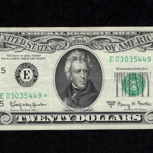Pode incluir: Uma nota de vinte dólares com um retrato de Andrew Jackson. A nota é verde e preta, com o texto "United States of America" e "Twenty Dollars". O número de série é E03035449*.
