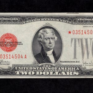 May include: A vintage two-dollar banknote featuring Thomas Jefferson. The bill has a red seal and serial number, with the text "TWO DOLLARS" displayed. The note is from the United States of America.