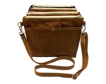 May include: A brown leather crossbody bag with multiple zippered compartments and a long adjustable strap.