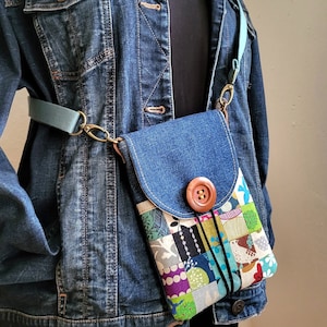 Könnte beinhalten: Eine Denim-Umhängetasche mit einer Klappe aus Patchwork-Stoff und einem großen Knopfverschluss. Die Tasche wird über einer Jeansjacke getragen.