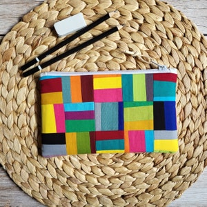 Könnte beinhalten: Eine bunte Patchwork-Stiftetui mit Reißverschluss. Die Etui ist aus Stoff mit verschiedenen Farben, darunter Rot, Grün, Blau, Gelb und Pink.