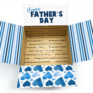 May include: Open cardboard box with a blue and white striped pattern on the outside and a blue watercolour heart pattern on the inside. The box has a sticker on the inside that says "Care Package Sticker" and "Thank you for using Priority Mail Service". The top of the box has the text "Happy Father's Day" printed on it.