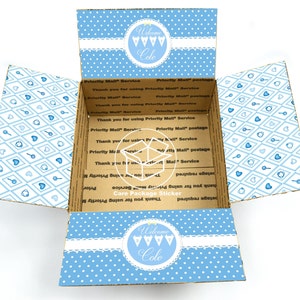 May include: An open cardboard box with a blue and white patterned design. The box has a white label with the text "Welcome Cole" and a blue and white polka dot pattern. The box is designed for shipping and has a "Care Package Sticker" label.