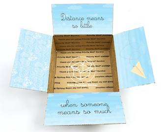 May include: A cardboard box with a blue and white patterned design. The box is open and the inside is lined with brown cardboard. The box has a sticker on the front that says "Distance means so little when someone means so much".