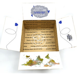 May include: A white cardboard box with a world map printed on the inside. The box is open and the top flap is folded back. The outside of the box has a blue and gray design with the text "Distance means so little someone means so much".