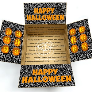 May include: A cardboard box with a black and white spiderweb pattern and the words "HAPPY HALLOWEEN" on the top and bottom flaps. The box is open and there are several orange jack-o'-lantern faces on the inside.