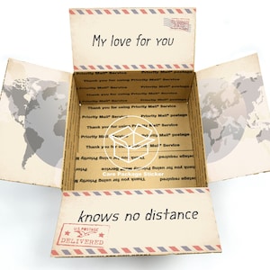 May include: A cardboard box with a world map design and the text "My love for you knows no distance" on the front. The box is open and has a "Care Package Sticker" on the inside.