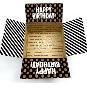 May include: A black and gold gift box with a polka dot pattern and the text "Happy Birthday!" on the top. The inside of the box is lined with black and white stripes.