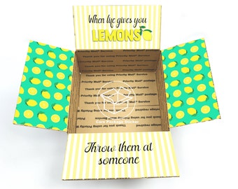May include: A cardboard box with a yellow and white striped pattern on the front and a lemon pattern on the sides. The box is open and the inside is visible. The text "When life gives you lemons" is printed on the front of the box. The text "Throw them at someone" is printed on the inside of the box.