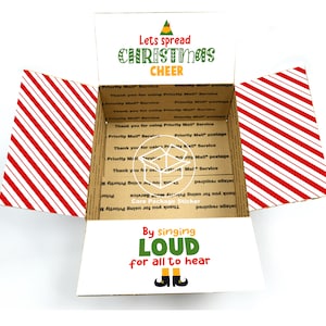 May include: A brown cardboard box with red and white striped paper lining the inside. The box is open and the inside has a sticker that says "Lets spread Christmas Cheer" with a green elf hat and a green elf shoe. The sticker also says "By singing LOUD for all to hear" with two green elf shoes.