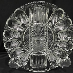 May include: A clear glass serving dish with a scalloped edge and a central divider. The dish has eight individual compartments, perfect for serving appetizers or snacks.