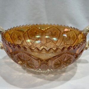 May include: A vintage amber glass bowl with two handles. The bowl has a scalloped edge and a cut glass design.