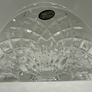 May include: A white ceramic mug with a black handle and the text "But First, Coffee" in a bold, black font. The mug is set against a blurred background, suggesting a cozy setting.