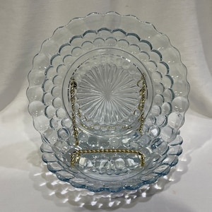 May include: Two clear blue glass plates with a bubbled rim and a starburst pattern in the center. The plates are stacked on top of each other.