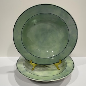 May include: Two green ceramic bowls with a white and green marbled design and a black rim. The bowls are stacked on top of each other.