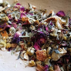 Op de afbeelding: Een close-up van een mengsel van gedroogde kruiden, bloemen en fruitschillen. De mix bevat gedroogde sinaasappelschil, rozenblaadjes, kamillebloemen en lavendelknoppen.