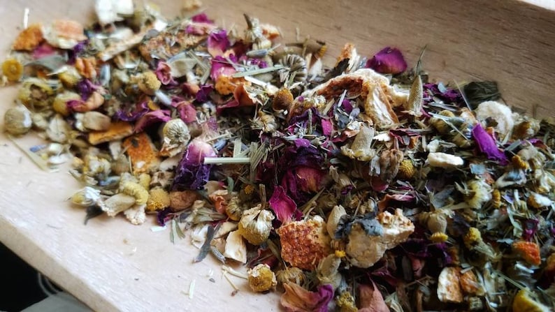 Op de afbeelding: Een close-up van een mengsel van gedroogde kruiden, bloemen en fruitschillen. De mix bevat gedroogde sinaasappelschil, rozenblaadjes, kamillebloemen en lavendelknoppen.