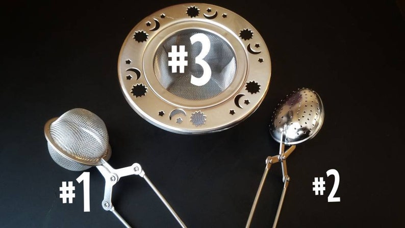 Op de afbeelding: Drie verschillende thee-infusers. De eerste is een ronde bal-infuser met een handvat. De tweede is een ronde infuser met een handvat en een veerbelaste opening. De derde is een ronde, platte infuser met een handvat en een decoratief ontwerp van sterren en manen.