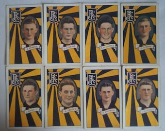 Könnte beinhalten: Acht Vintage-Sammelkarten mit Schwarzweißfotos von Männern in Fußballtrikots. Jede Karte hat einen gelben und schwarzen gestreiften Hintergrund mit einem Wappen, auf dem "R" in der Mitte steht. Die Namen der Spieler sind unter ihren Fotos aufgedruckt.