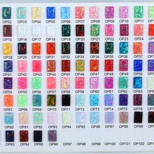 May include: A chart of 104 small, square, opal cabochons, arranged in rows and columns. The cabochons are various colors, including white, black, blue, green, red, pink, and orange. Each cabochon is labeled with a number, starting with OP01 and ending with OP104.