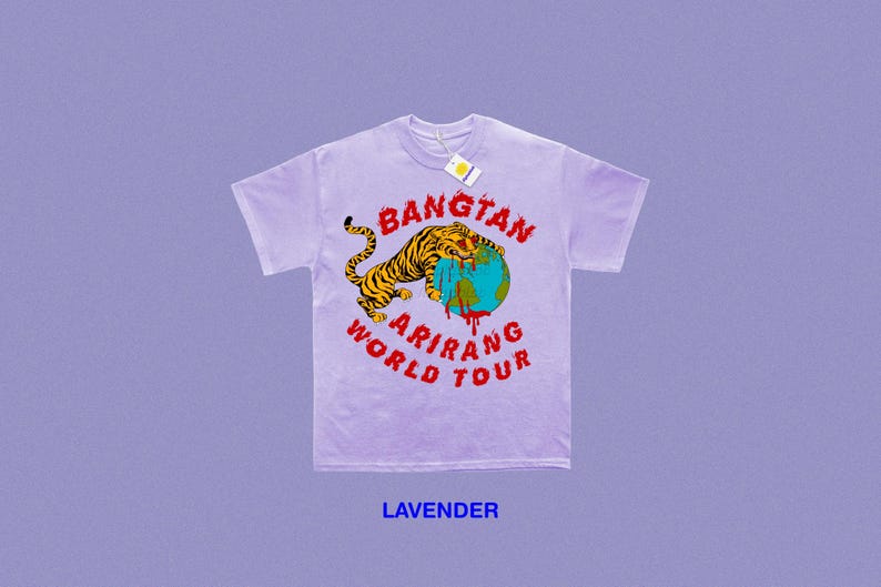 May include: Lavender t-shirt with a graphic featuring a tiger wrapped around a globe, with the words "BANGTAN ARIRANG WORLD TOUR" in red. The tiger is yellow and black. A tag hangs from the collar.