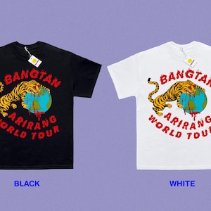 May include: Black and white t-shirts with a graphic design. The design features a tiger over a globe with the words "BANGTAN ARIRANG WORLD TOUR" in red. Each shirt has a tag attached.