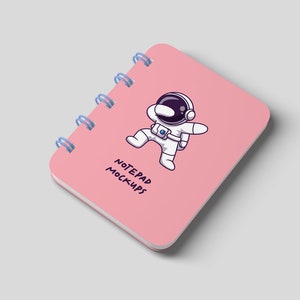 May include: Pink notepad mockup with a spiral binding and a cartoon astronaut illustration. The notepad says "Notepad Mockups".