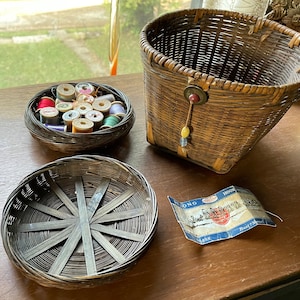 May include: Three woven baskets, one with a variety of spools of thread, another with a blue and white label that reads "Hook 1000", and a third empty basket.