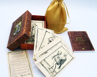 May include: A set of tarot cards in a brown box with a gold drawstring bag. The cards are laid out on a white surface. The cards feature black and white illustrations of people and symbols. The box has the text "Tarocchi Mantegna Ladenspieler" on the front. The bag is made of a soft, silky fabric.