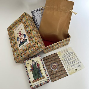May include: A tarot card set featuring a patterned box, a brown drawstring bag, and several cards. One card displays "L'imperatrice The Empress". The box is labelled "TRINACRIA 1930".